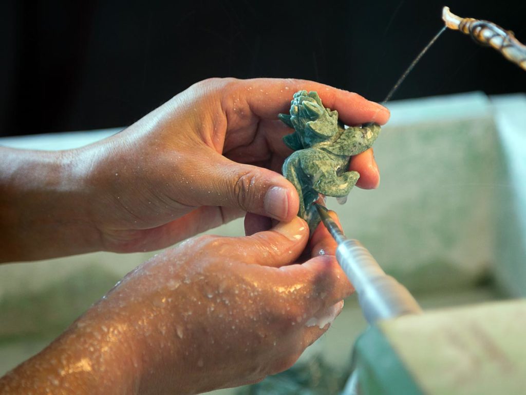 An artisan meticulously carving a piece of jade.